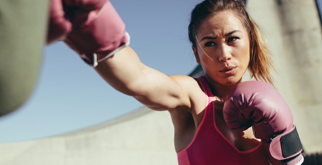 Dziewczyna w różowych rękawicach bokserskich podczas treningu PT boxing w Holmes Place