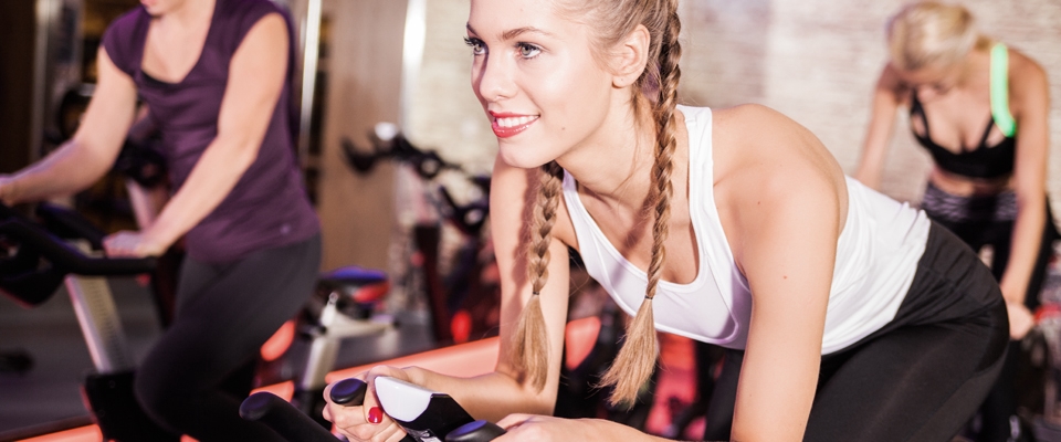 indoor cycling gym fitness women smile | Holmes Place